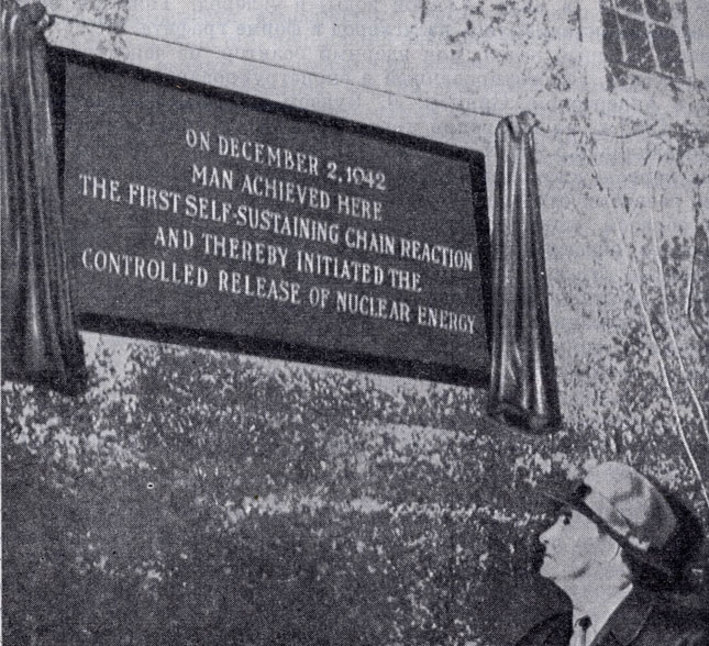Энрико Ферми у мемориальной доски, установленной на наружной стене теннисного корта Чикагского университета, где им был запущен первый атомный котел. Надпись на доске гласит: 'Здесь 2 декабря 1942 г. человек впервые осуществил цепную реакцию и этим положил начало овладению освобожденной ядерной энергией'